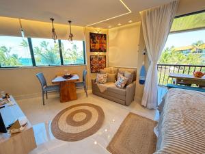 a bedroom with a bed and a couch and a table at Marulhos resort Muro Alto flats Premium frente ao mar in Porto De Galinhas
