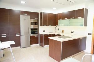 a kitchen with wooden cabinets and a refrigerator at Welcome Villa O Sidrón in Alba