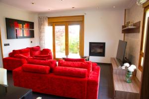 a living room with red furniture and a red couch at Welcome Villa O Sidrón in Alba