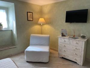 a living room with a white chair and a dresser at Residenza La Gemma in Subiaco