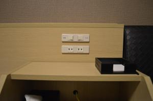 une chambre avec un interrupteur et une boîte sur une étagère dans l'établissement Hotel Route-Inn Takaoka Ekimae, à Takaoka
