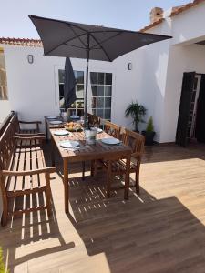 a wooden table with chairs and an umbrella at North Wind House in Peniche