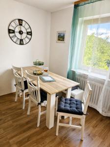 a dining room table with chairs and a clock on the wall at Ferienwohnung Panoramablick Bermersbach in Forbach