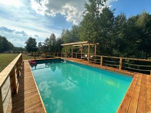 a swimming pool on a wooden deck with a gazebo at Leśna Stodoła in Siennica