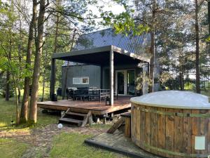 a tiny house with a hot tub on a deck at Leśna Stodoła in Siennica