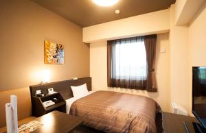 a hotel room with a bed and a window at Hotel Route-Inn Yanagawa Ekimae in Yanagawa
