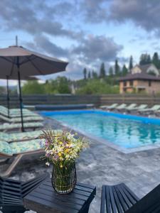 a vase of flowers sitting on a table next to a swimming pool at котедж петриківка З червня басейн з підігрівом 10 на 5 метрів in Slavske