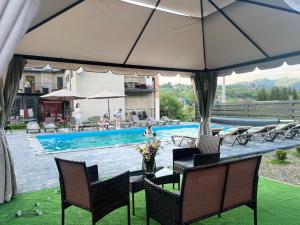 a table and chairs under an umbrella near a swimming pool at котедж петриківка З червня басейн з підігрівом 10 на 5 метрів in Slavske