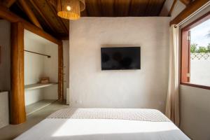a bedroom with a bed and a tv on the wall at Casa Caroá - Chalé 3 in Japaratinga