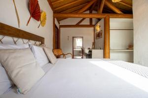 a bedroom with a large white bed with wooden ceilings at Casa Caroá - Chalé 3 in Japaratinga +68 photos
