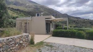 a white building with a mountain in the background at Villa Aias- Private Olive Grove Retreat in Plakias