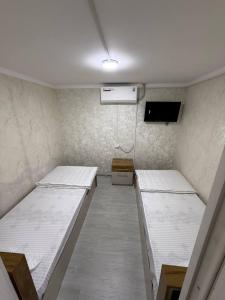 a room with two beds and a tv in it at Noor house hostel in Fergana