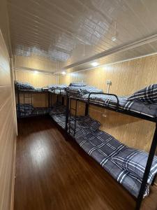 three bunk beds in a room with a wooden floor at Noor house hostel in Fergana