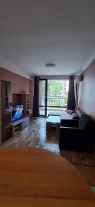 a living room with a couch and a tv at Atliman Beach Apartment 1 in Kiten
