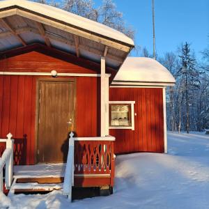 a red cabin with a wooden door in the snow at Rustic Old Lakeside Cottage at Sevettijärvi in Sevettijärvi