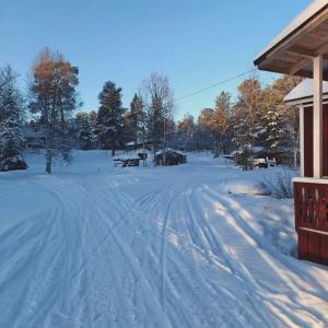a driveway covered in snow next to a house at Rustic Old Lakeside Cottage at Sevettijärvi in Sevettijärvi