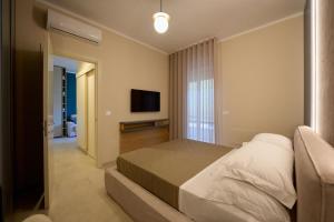 a bedroom with a bed and a flat screen tv at Oltremare Luxury Suites in Otranto