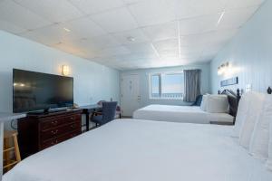 a bedroom with two beds and a desk and a tv at Sea View Inn in Old Orchard Beach