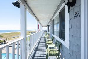 a porch with chairs and the ocean in the background at Sea View Inn in Old Orchard Beach