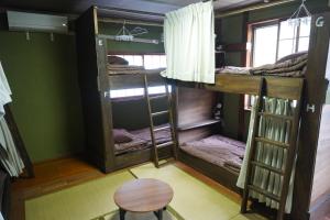 a room with bunk beds and a table at Backpacker's House Kamome in Fujiyoshida