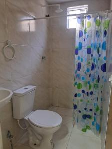 a bathroom with a toilet and a shower curtain at Kitnet Praia de Alagoinhas in Fortaleza