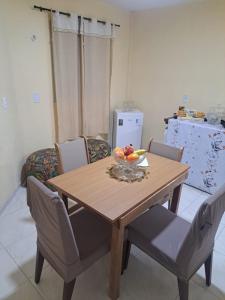 a wooden table with chairs and a bowl of fruit on it at Kitnet Praia de Alagoinhas in Fortaleza