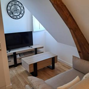 a living room with a tv and a clock on the wall at le pomerol in Château-Gontier
