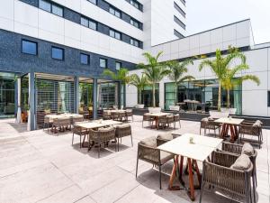 eine Außenterrasse mit Tischen und Stühlen und ein Gebäude in der Unterkunft Movenpick Hotel Abidjan in Abidjan