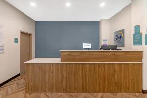 a reception desk in a room with a blue wall at Sleep Inn & Suites Pensacola - University Area in Pensacola