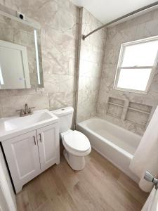 a white bathroom with a toilet and a tub and a sink at Sea Kist Motel in Wildwood +8 photos