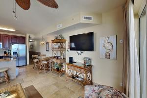 a living room with a television and a dining room at Beach Club #206A in Pensacola Beach