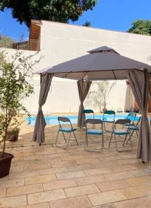 a table and chairs under an umbrella next to a pool at Suíte Aconchegante com Hidromassagem Jardim Esplanada in São José dos Campos