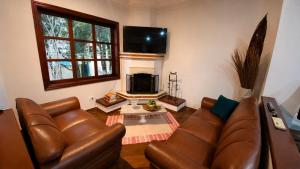 a living room with a leather couch and a fireplace at Suíte Aconchegante com Hidromassagem Jardim Esplanada in São José dos Campos