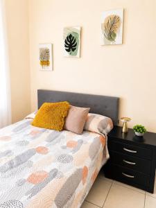 a bedroom with a bed with a nightstand and pictures on the wall at Estudio #5 a 5 min del malecon in La Paz