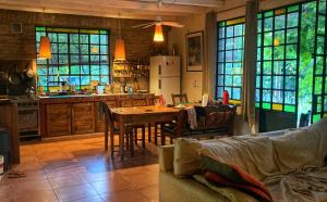 a kitchen with a table and chairs and a kitchen with windows at Las Pircas, casa de campo in Ciudad Lujan de Cuyo