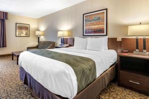 a hotel room with a large bed and a chair at Quality Inn & Suites Escanaba North in Escanaba