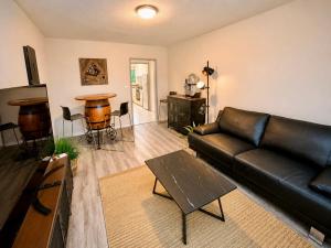 a living room with a black leather couch and a table at 3Br Topview Interlaken Mountain View Apartment in Unterseen