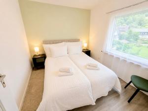 a bedroom with a large white bed with a window at 3Br Topview Interlaken Mountain View Apartment in Unterseen