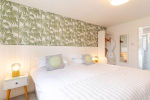 a bedroom with a white bed with a tropical wallpaper at Porth Beach Hotel in Newquay +73 photos