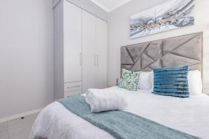a white bedroom with a large bed with blue pillows at Zoe Lodge in Midrand +12 photos
