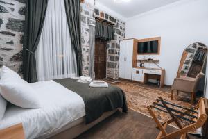 a bedroom with a bed and a chair and a television at Kremlin 1908 Hotel in Kars