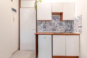 a kitchen with white cabinets and blue and white tiles at Beachfront Studio Free Parking-Pool 50m from Sea in Chioggia