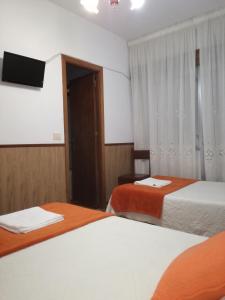 a hotel room with two beds and a flat screen tv at Pensión Los Trillizos in Boiro