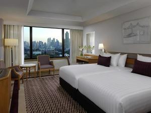 a hotel room with a large bed and a large window at Grand Mercure Bangkok Atrium in Bangkok