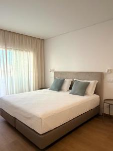 a bedroom with a large white bed with blue pillows at Entrecubos Apartamentos in Olhão