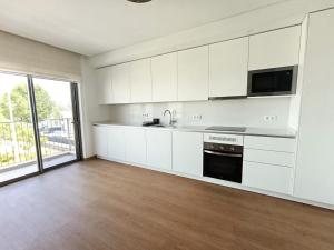 a kitchen with white cabinets and a large window at Entrecubos Apartamentos in Olhão