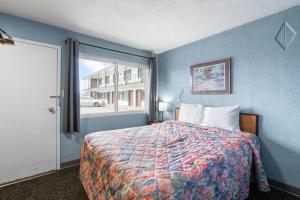 a blue bedroom with a bed and a window at Broadway Inn in Council Bluffs