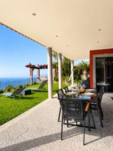 a patio with a table and chairs and the ocean at Casa do Piquinho in Ponta do Sol