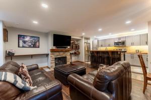 a living room with two leather couches and a fireplace at Wild Irishman #1030 in Keystone