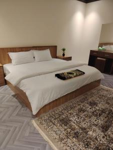 a bedroom with a large bed and a rug at Sukoon Apartment شقة سكون 2 in Buraydah